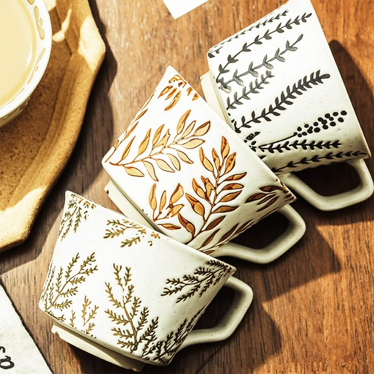 four coffee cups sitting on top of a wooden table