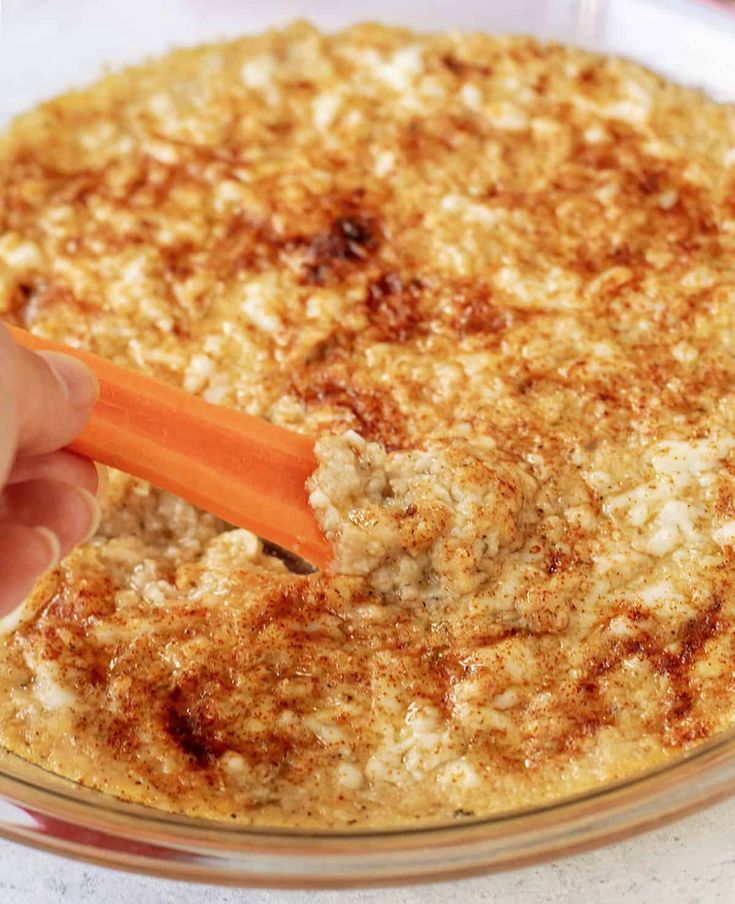 a person is holding an orange carrot in a casserole dish