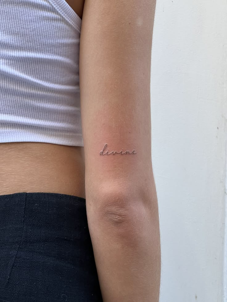 a woman's arm with the word love tattooed on her left arm, in cursive font