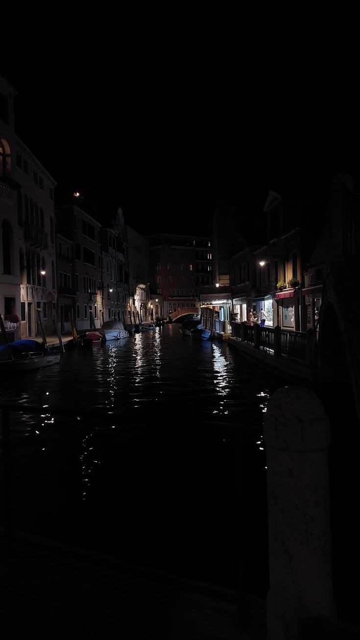 a canal at night with boats in the water and buildings on both sides, all lit up by street lamps