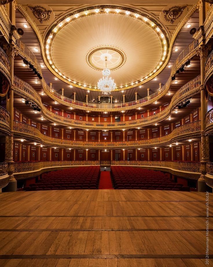 an empty auditorium with chandelier and wooden floors