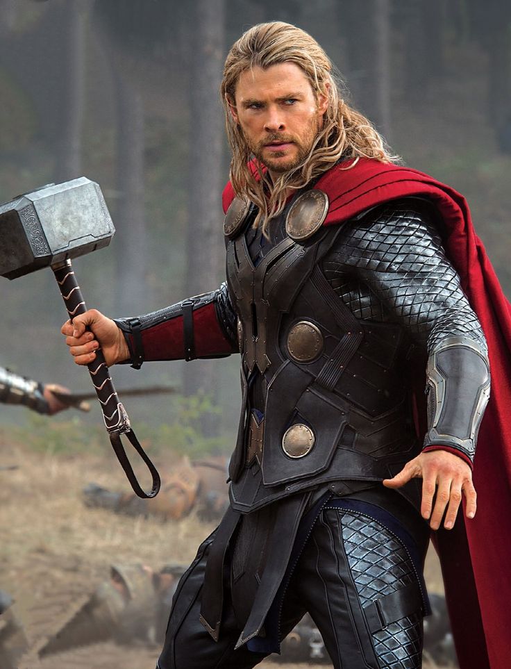 thor is holding an ax in his hand and looking at the camera while another man stands behind him