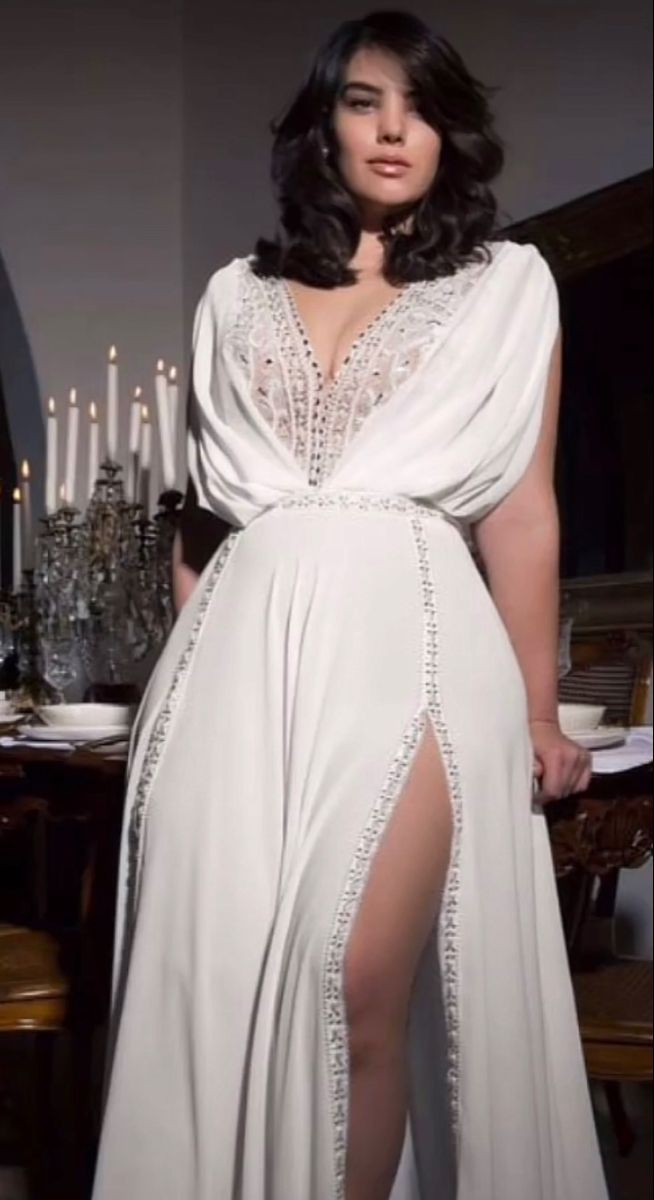 a woman wearing a white dress with a slit in the thigh and an open back