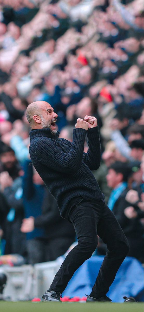 a man with a beard standing in front of a crowd at a soccer game, holding his fist up