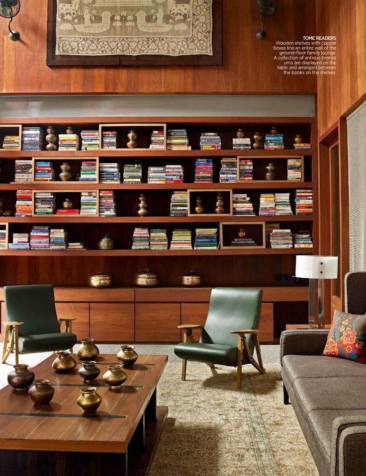 a living room filled with lots of furniture and bookshelves on the wall above