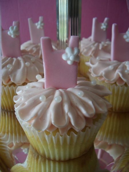 cupcakes decorated with pink frosting and white icing are displayed in front of a mirror