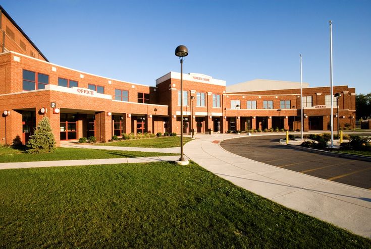 an empty street in front of a brick building with lots of windows and lights on it