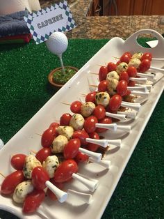 some food is laying out on a long white tray with toothpicks in them