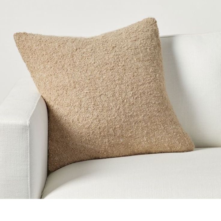 a beige pillow sitting on top of a white couch