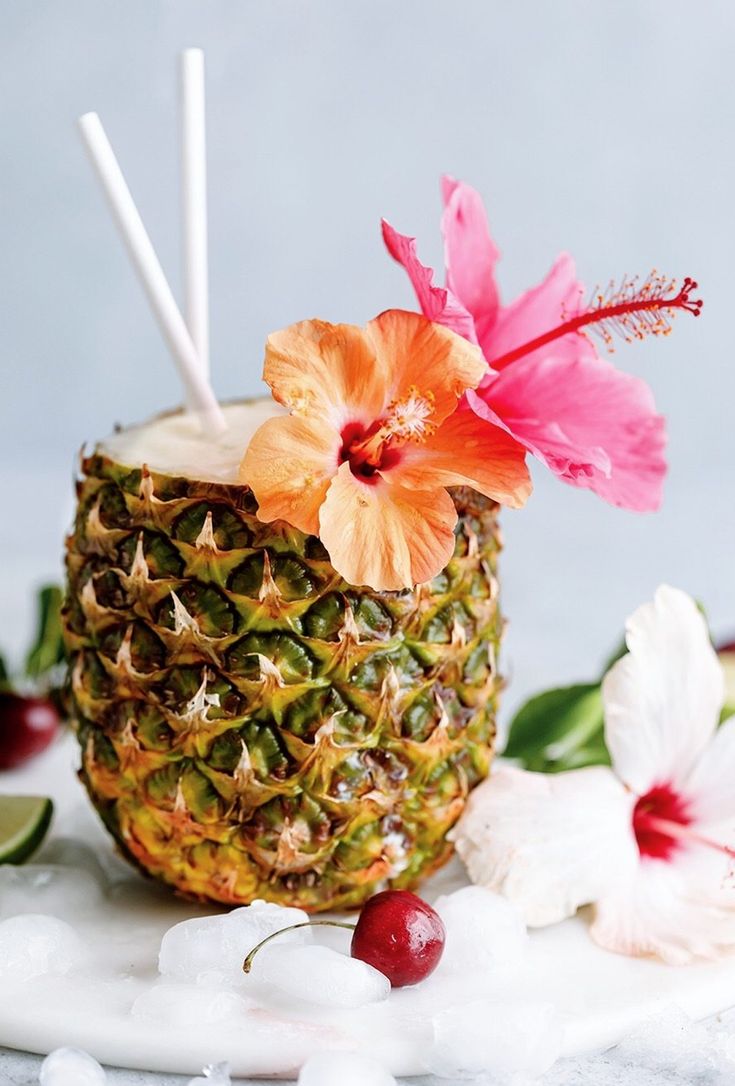 a pineapple drink with two straws and flowers