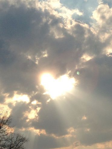 the sun shines brightly through the clouds above some trees