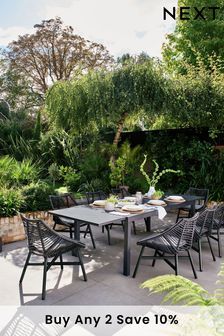 an outdoor dining table surrounded by plants and trees