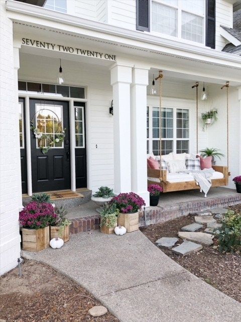 the front porch of a white house with black doors