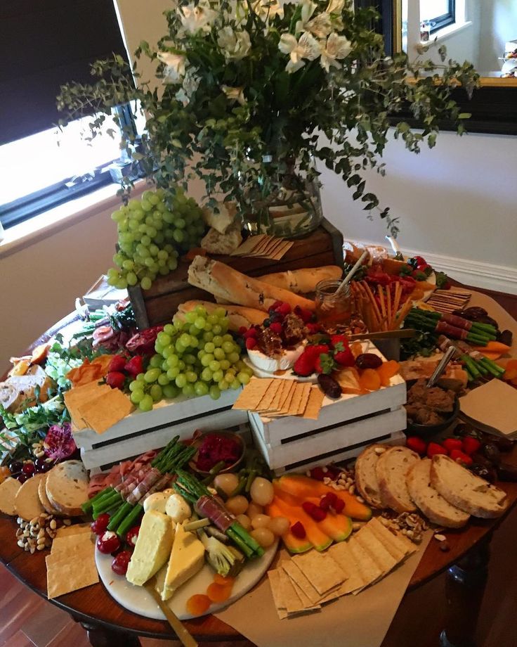 a table topped with lots of different types of cheeses and crackers next to a potted plant