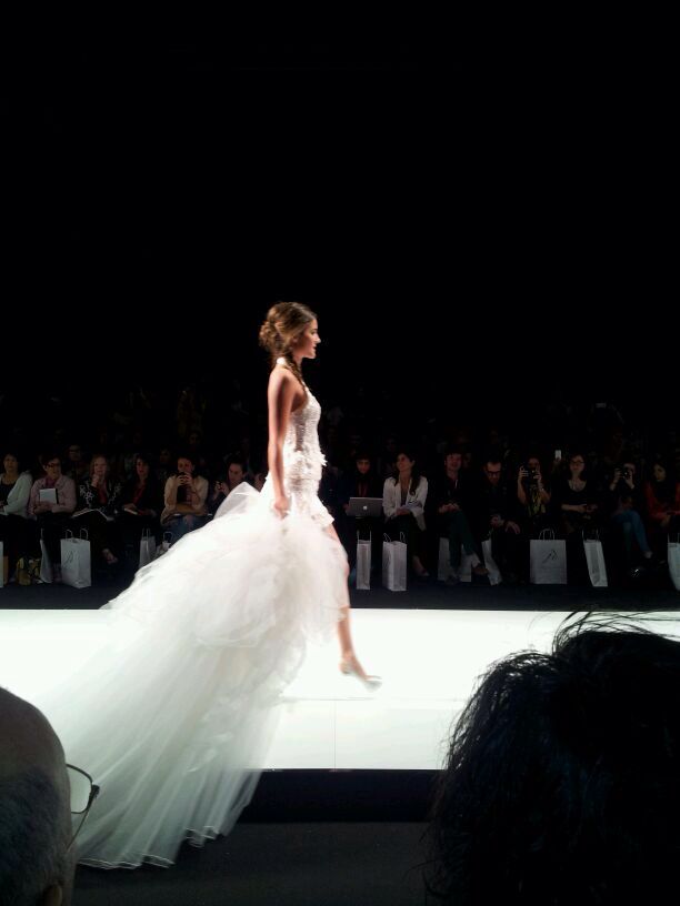 a woman in a white dress walking down a runway