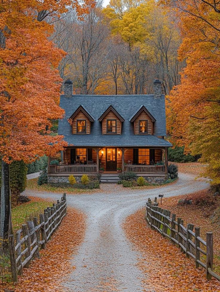 a large house surrounded by trees with fall leaves on the ground in front of it