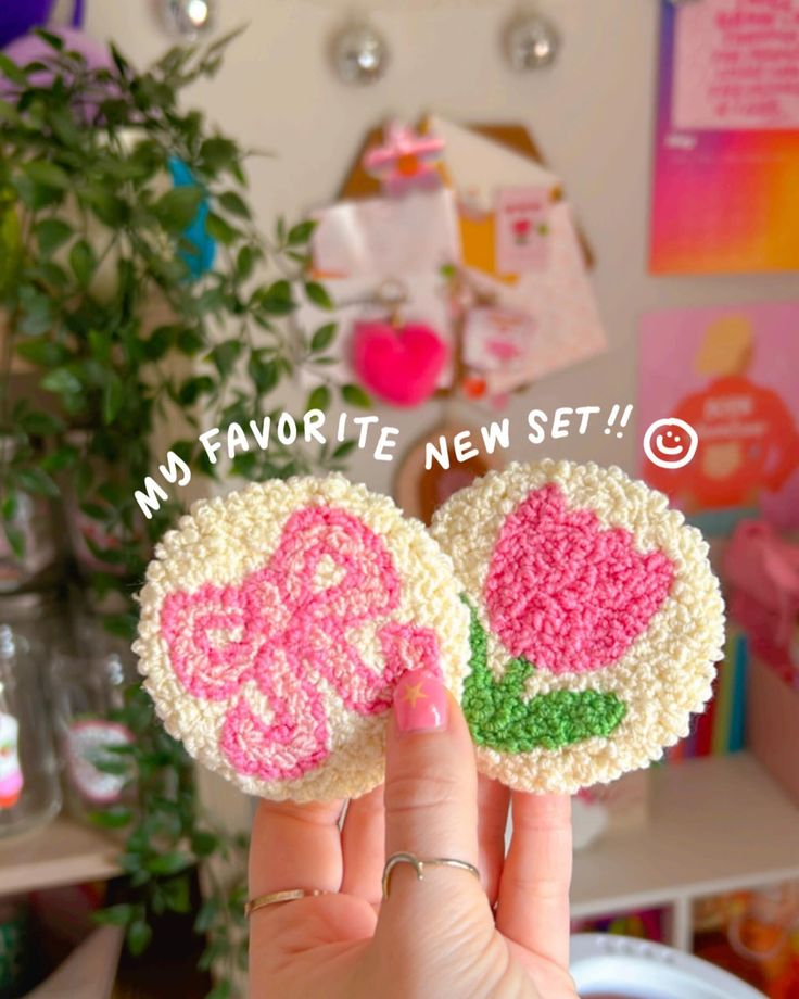 two small crocheted flowers on top of each other in front of a plant