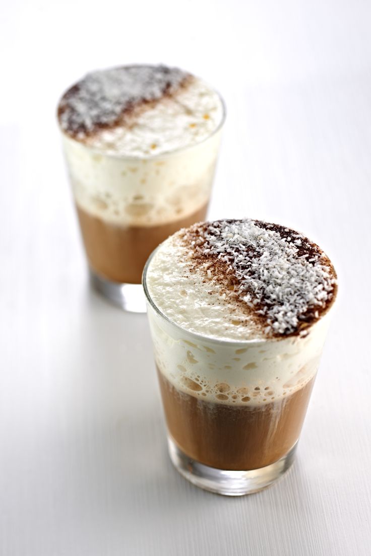 two glasses filled with dessert sitting on top of a white table next to each other