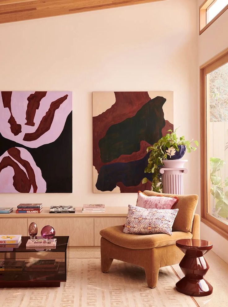 a living room filled with furniture and paintings on the wall next to a coffee table