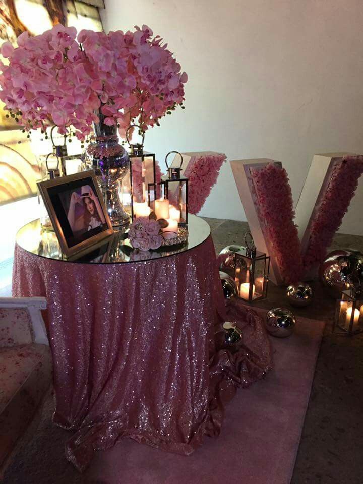 a table with pink flowers and candles on it next to two large letters that spell out the word love