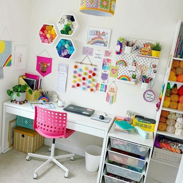 a white desk topped with a pink chair next to a shelf filled with lots of crafting supplies