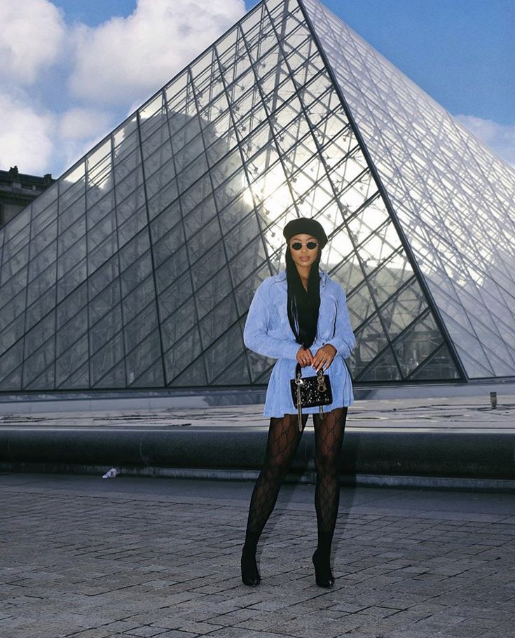 a woman standing in front of a very tall pyramid