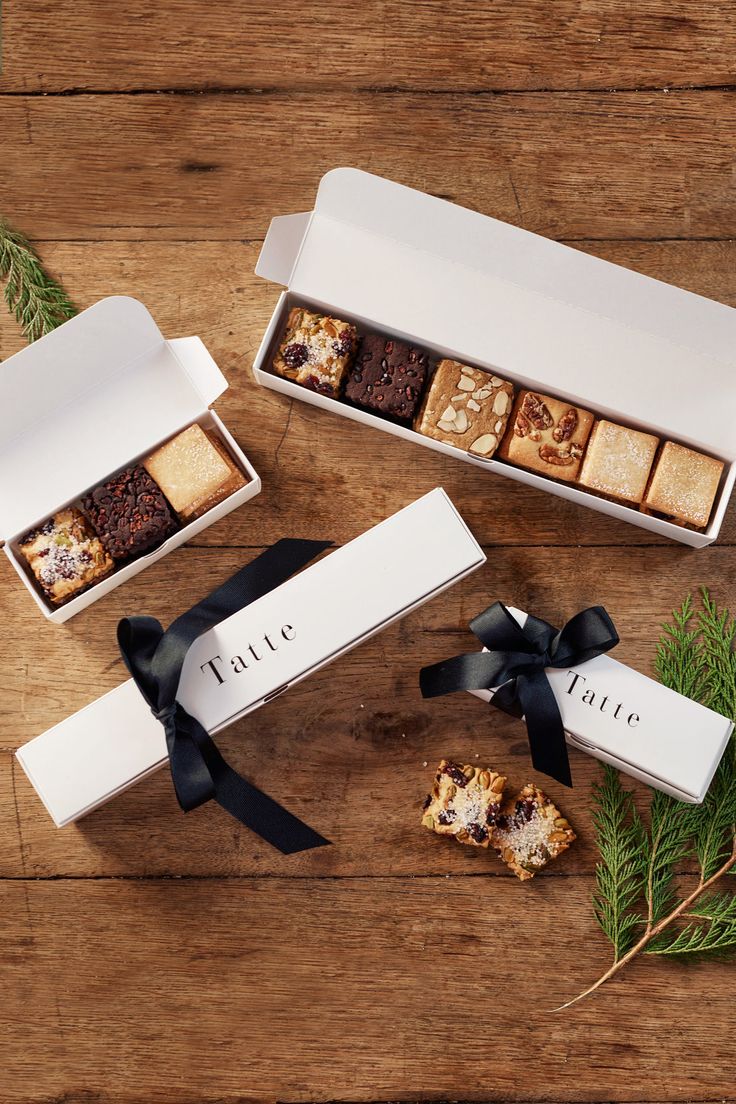 two boxes of cookies and one box of crackers with black ribbon on wooden table