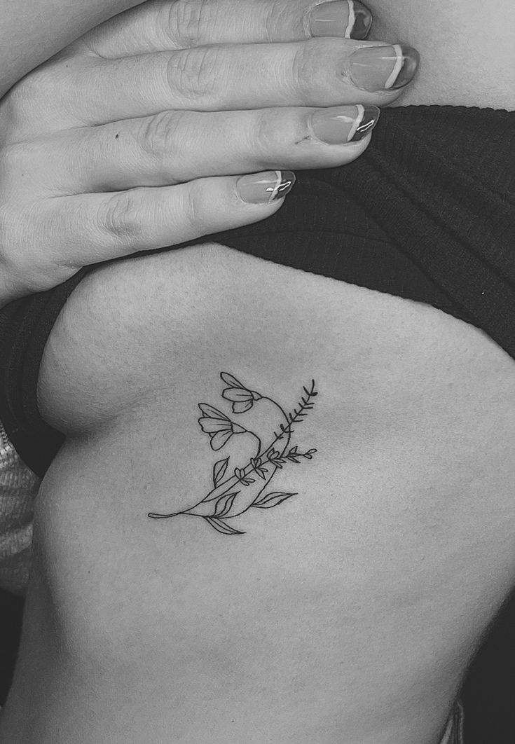 a black and white photo of a woman's stomach with a flower tattoo on it