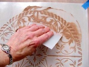 a person is using a piece of paper to cut out decorative designs on a wall