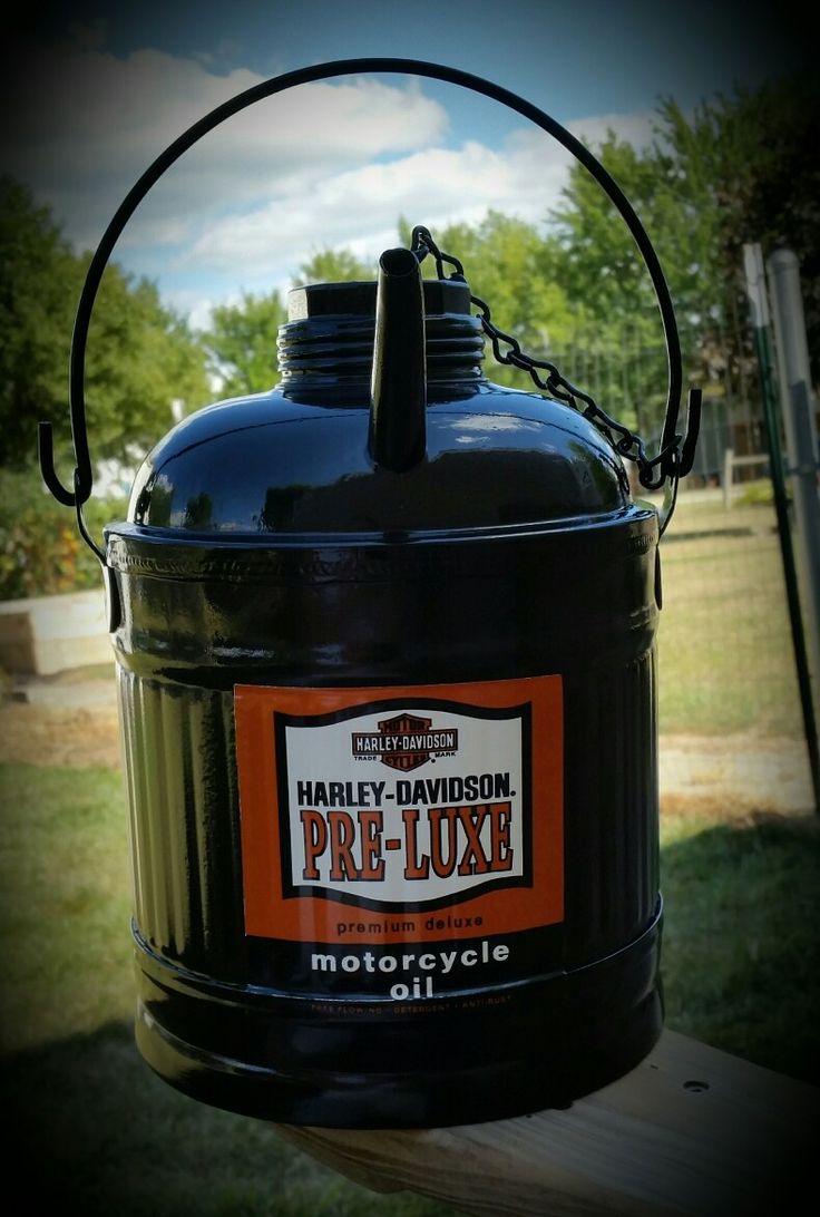 a large black oil can sitting on top of a wooden table next to a field