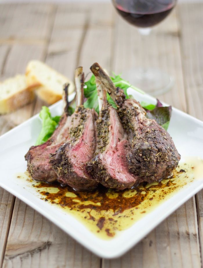 a white plate topped with meat next to a glass of wine