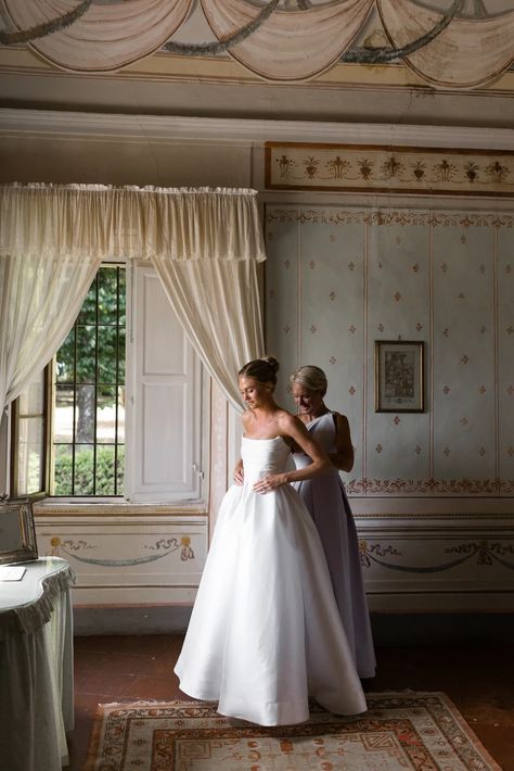 two brides standing in front of a window with drapes on the windowsill