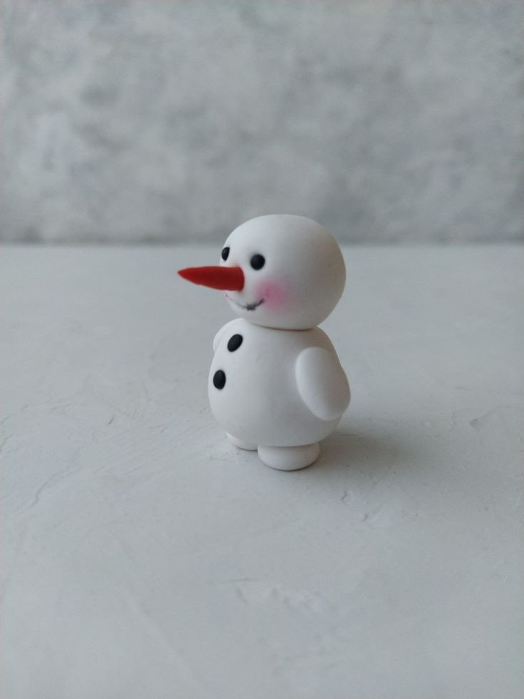 a small white snowman with red nose and black dots on it's body