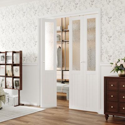 a bedroom with white walls and wood flooring, decorated in floral wallpapers