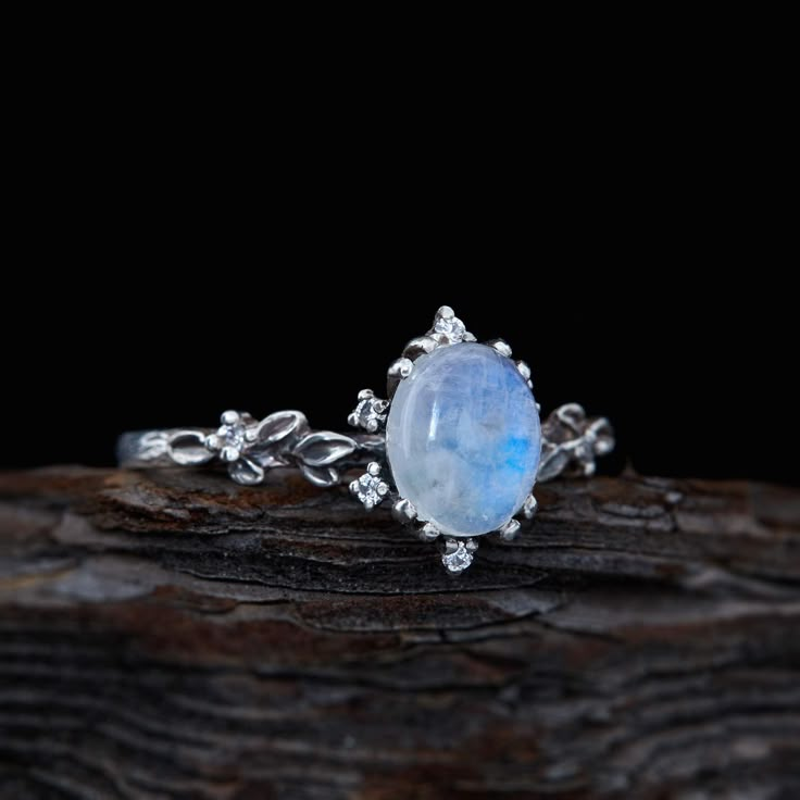 a ring with a blue and white stone in the center on top of a piece of wood