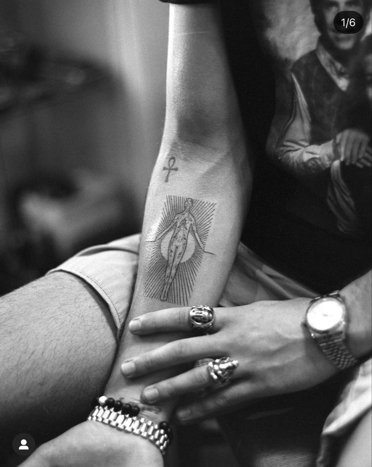 black and white photo of two people holding each other's hands with tattoos on them