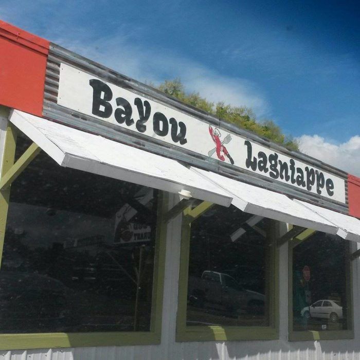 the sign on the building says bayou and lashabpe in black letters, with cars parked outside