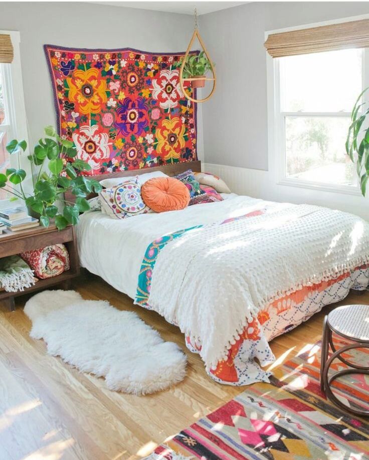 a room with a bed, rugs and plants in it