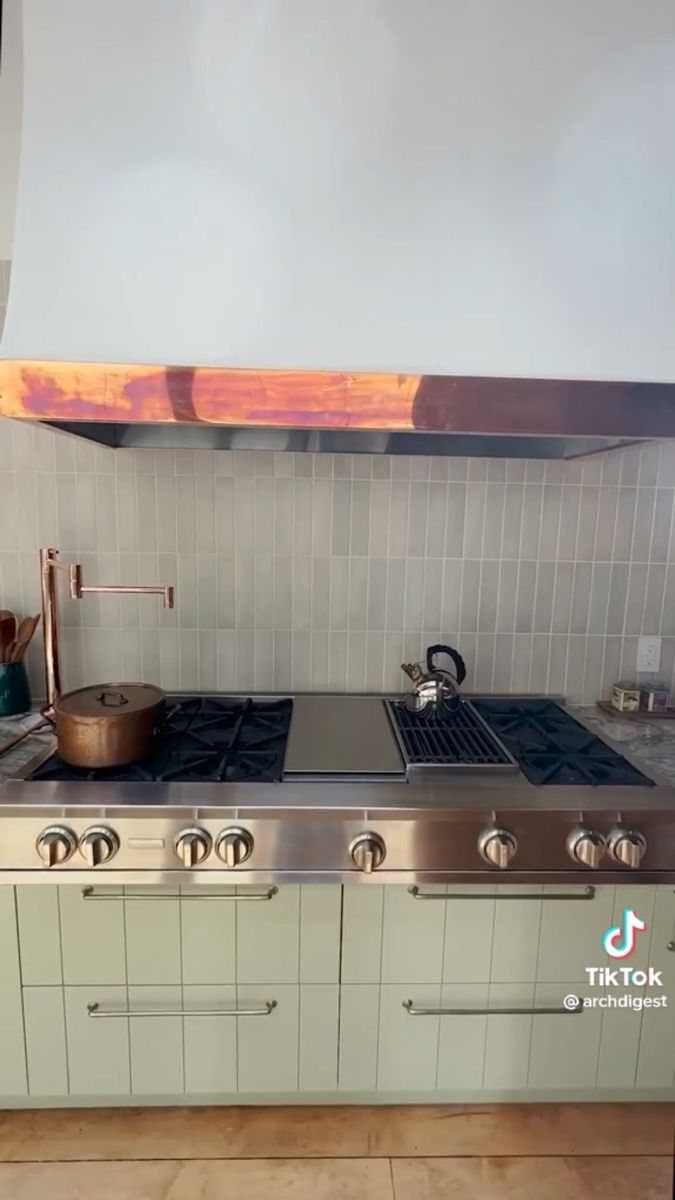 a stove top oven sitting inside of a kitchen next to a wall mounted range hood