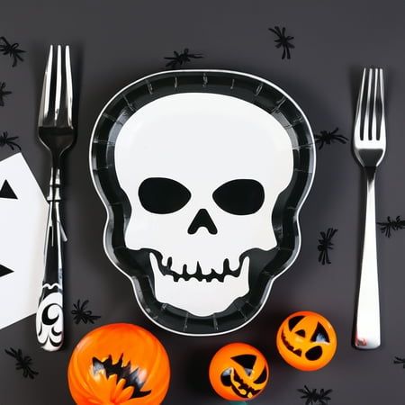 a plate with a skull on it next to two jack - o'- lanterns