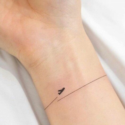 a small tattoo on the wrist of a person with a bird sitting on a wire