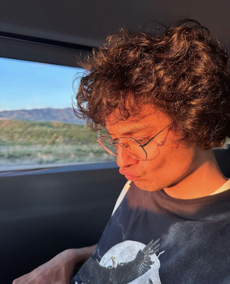 a man sitting in the back seat of a car looking down at his cell phone