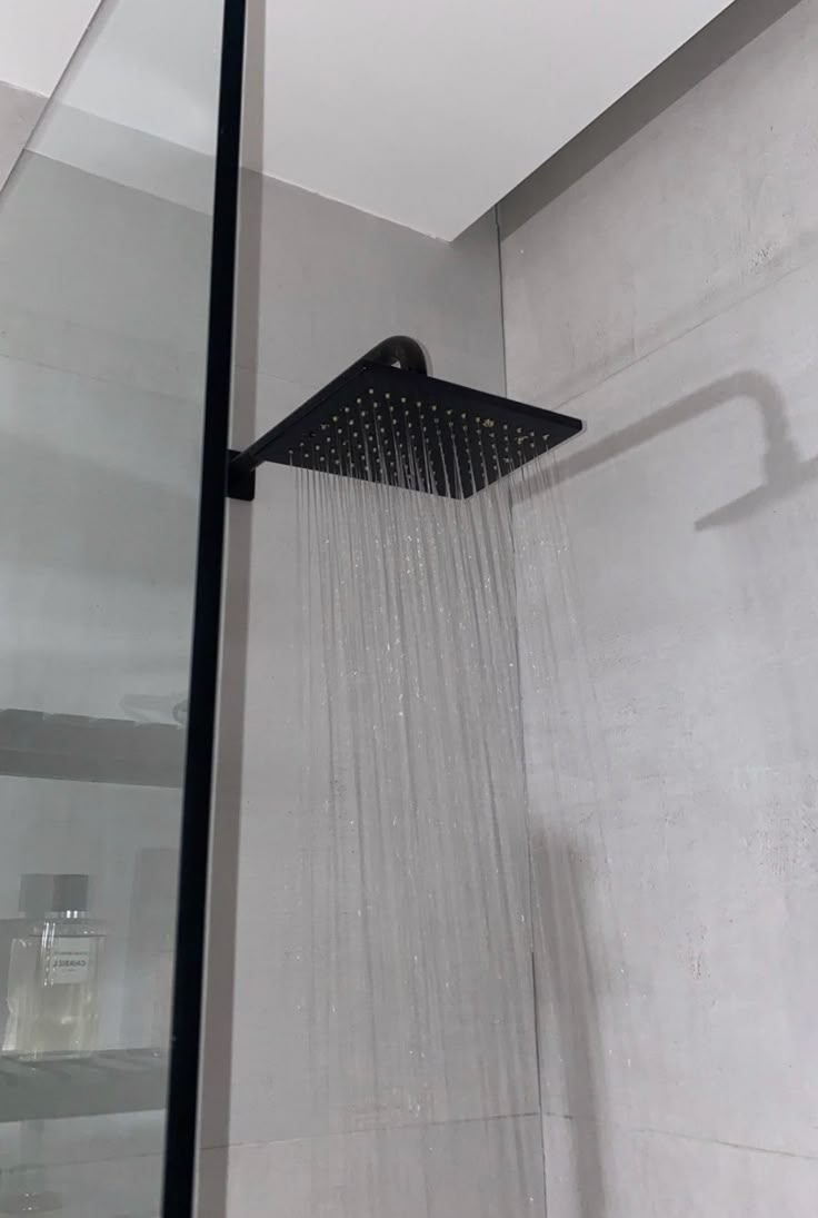 an overhead shower head with the rain running down it's side and water coming out