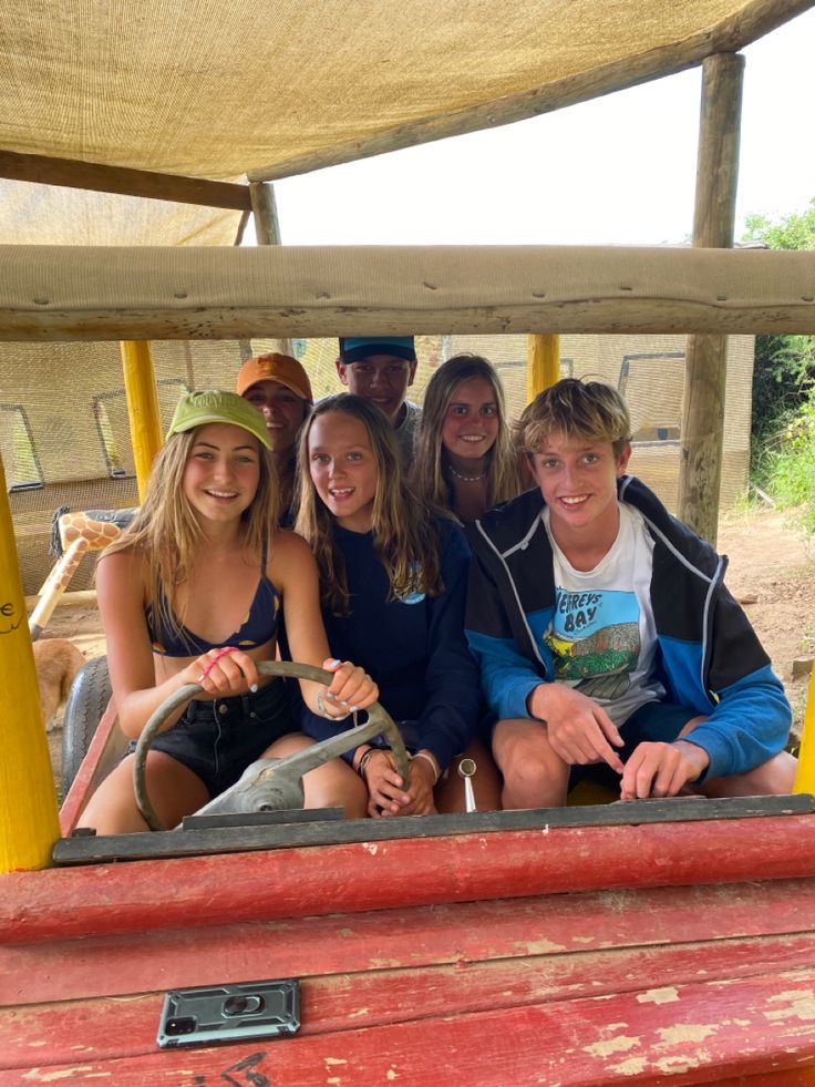 a group of young people riding on the back of a red truck