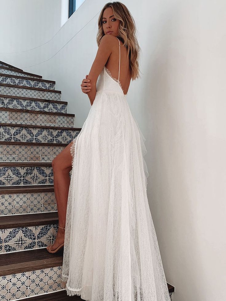 a woman in a white dress standing on some stairs