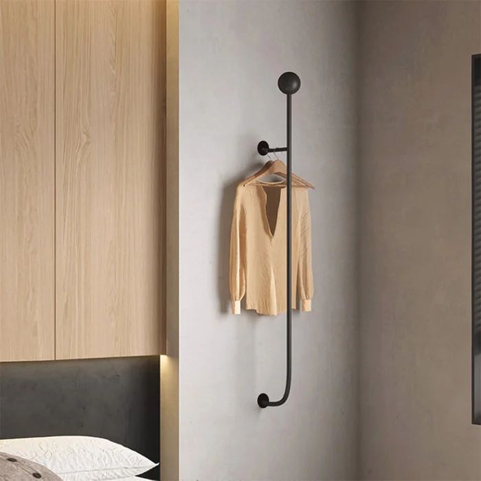 a bedroom with a bed, mirror and coat rack on the wall next to it