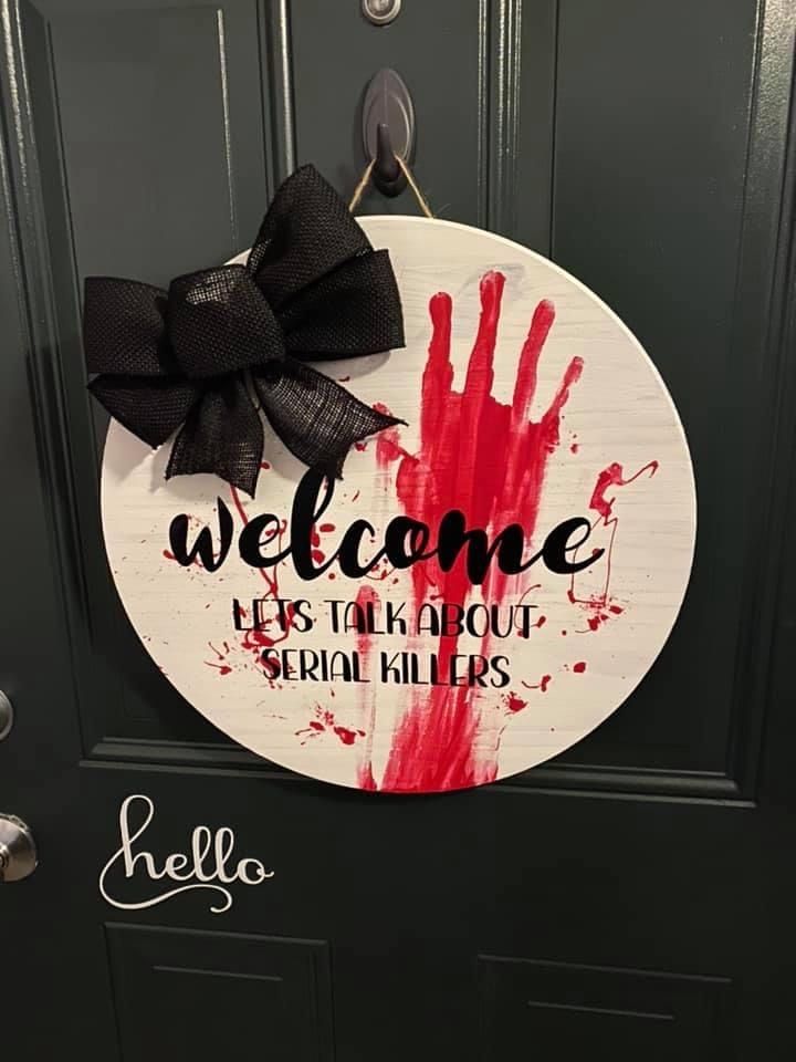 a welcome sign hanging on the front door to someone's house that has been painted red and black