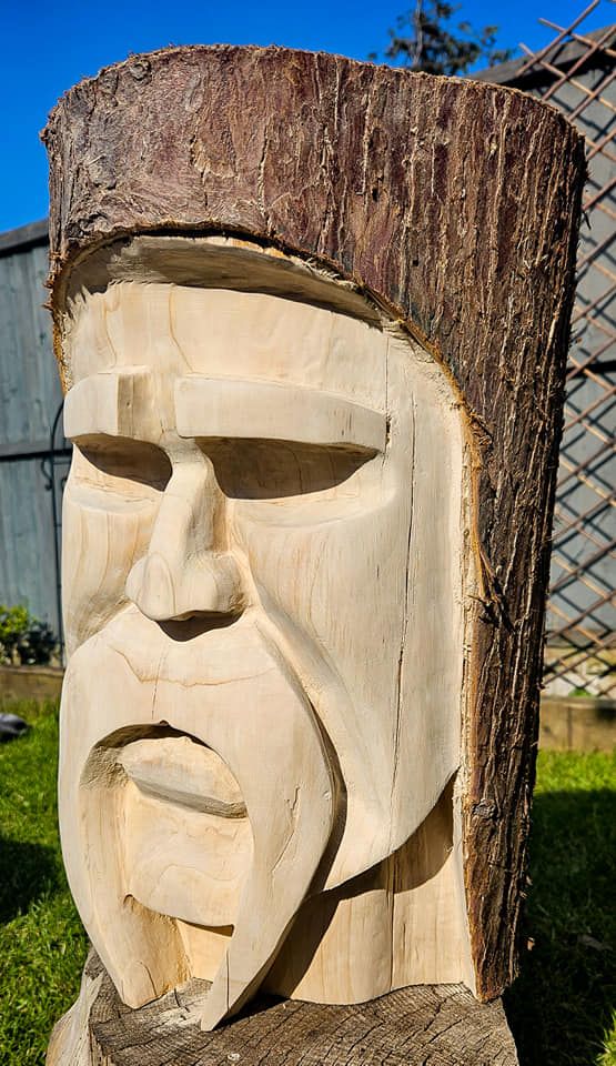 a carved wooden face sitting on top of a tree stump