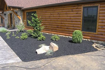 a house with a driveway and landscaping in front of it that has rocks on the ground