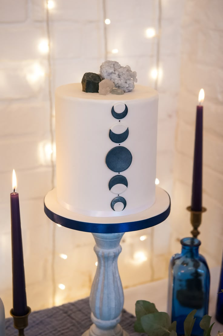 a white cake sitting on top of a table next to two candles and some rocks